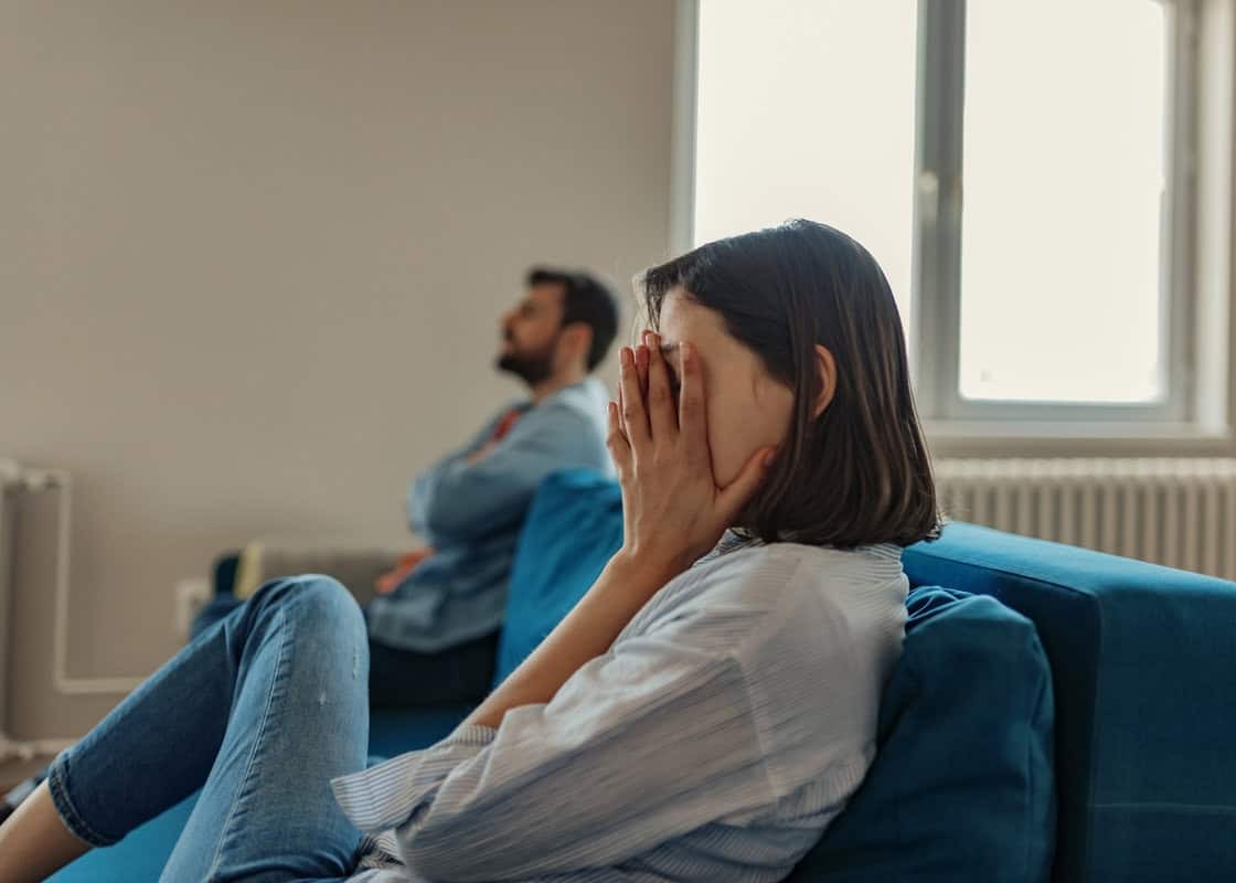 Unhappy Couple After an Argument in the Living Room at Home. Sad Pensive Young Girl Thinking of Relationships Problems Sitting on Sofa With Offended Boyfriend, Conflicts in Marriage, Upset Couple After Fight Dispute, Making Decision of Breaking Up Get Div
