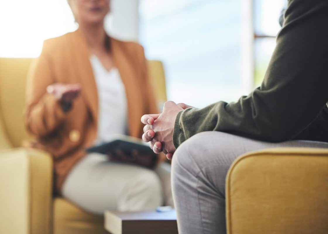 Man, hands and listening for therapy, sofa or advice from woman for mental health, psychology or care. Psychiatrist, patient and frustrated in clinic, session or couch for help, anxiety or depression