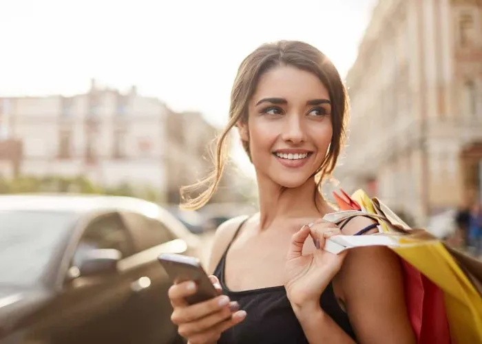 Positive emotions. Lifestyle concept. Close up of young charming dark-haired caucasian woman in black dress smiling with teeth, looking aside with relaxed expression, chatting with boyfriend on phone