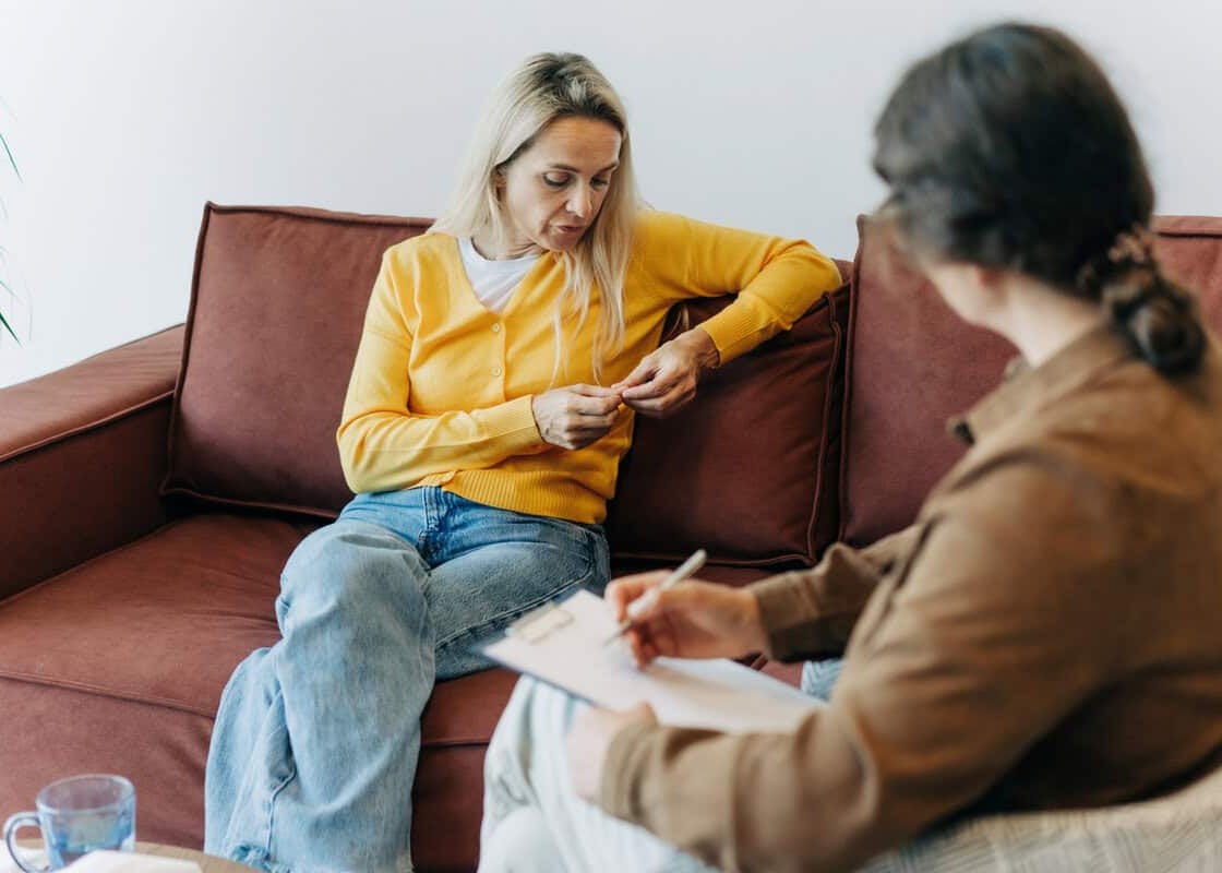 A woman patient, sitting on the couch during a consultation with a psychologist, talks about her difficulties in life, stress and relationship problems.