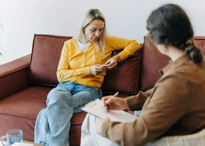 A woman patient, sitting on the couch during a consultation with a psychologist, talks about her difficulties in life, stress and relationship problems.