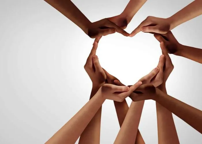 Unity and diversity partnership as heart hands in a group of diverse people connected together shaped as a support symbol expressing the feeling of teamwork and togetherness.
