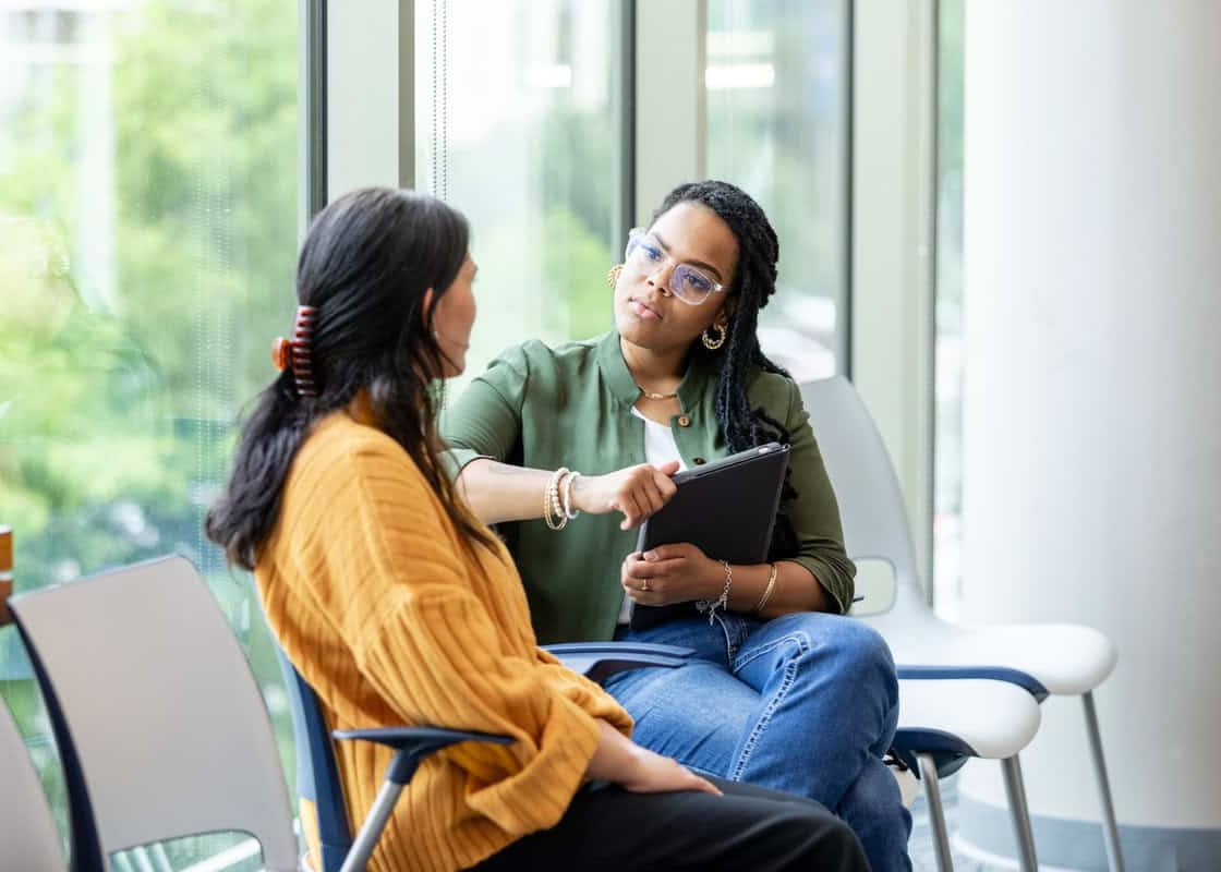 An empathetic female counselor listens as a vulnerable patient shares about a difficult situation.