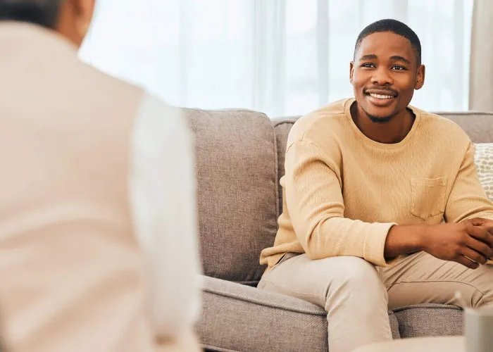 Black man, counseling and psychology consulting for therapy, mental healthcare or support. Happy patient talking to psychologist, therapist and medical help in consultation, advice and wellness check