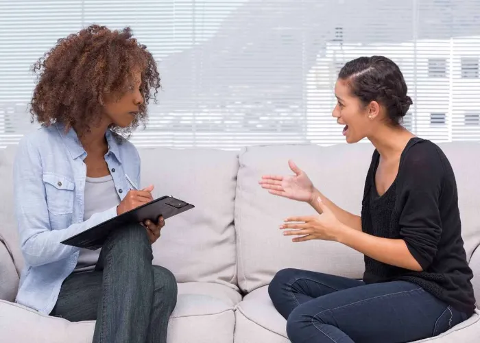 Upset woman speaking to her therapist while she is taking notes