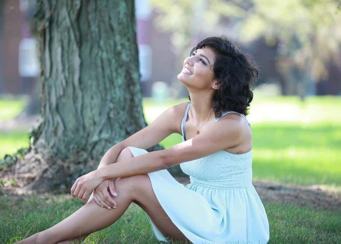 Beautiful hispanic girl sitting on the grass looking to the sky