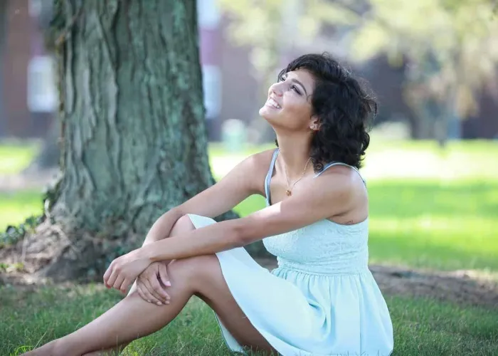 Beautiful hispanic girl sitting on the grass looking to the sky
