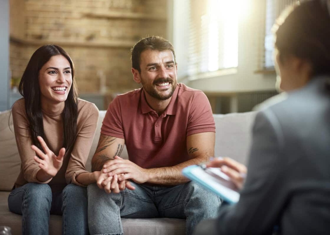 Young happy couple talking about their love with a marriage counselor at home.